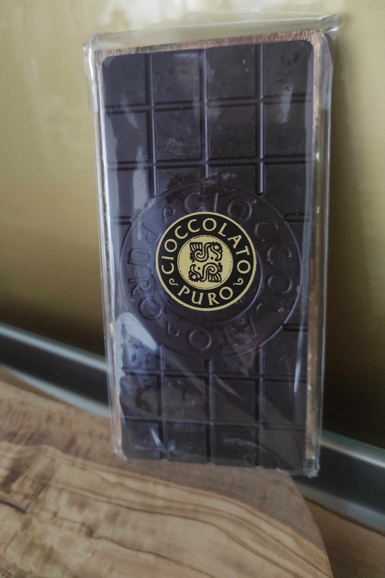 Eine 100% Criollo Edel-Kakaotafel, 100g, in einer durchsichtigen Verpackung, die die reichhaltige Textur der dunklen Schokolade zur Geltung bringt.