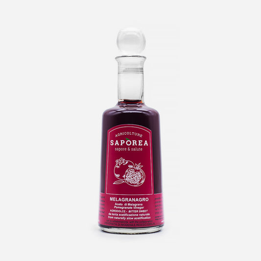 Schlanke Glasflasche mit Saporea Essig, klarer Glasstopfen, leuchtendes pinkes Etikett, Fruchtillustrationen.