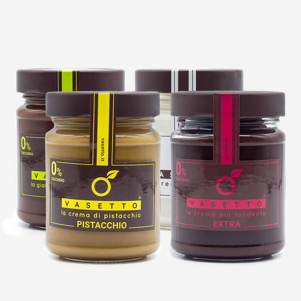 Vier Gläser Vasetto vegane Aufstriche in Geschmacksrichtungen wie Pistazie und Extra mit bunten Etiketten in Geschenkbox.
